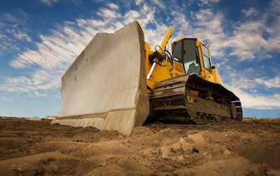 Bulldozer moving a precast concrete barrier on site